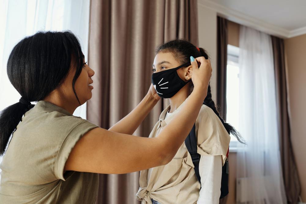 An adult placing a mask on a child