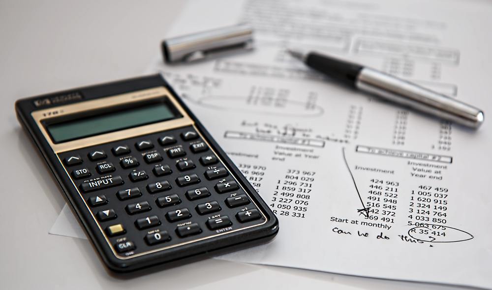 An image of a calculator and pen sitting on what appears to be a financial record sheet