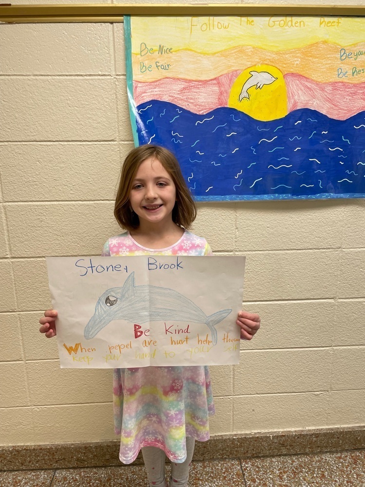 During The Great Kindness Challenge some of our Stony Brook students showed off their I Am posters and also took a nice breathing break with some yoga. Female student holding up her dolphin drawing with stony brook's name and be kind words